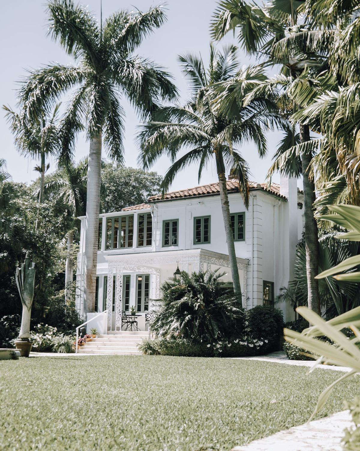 Palm-lined entry to a white Mediterranean-style home in West Palm Beach